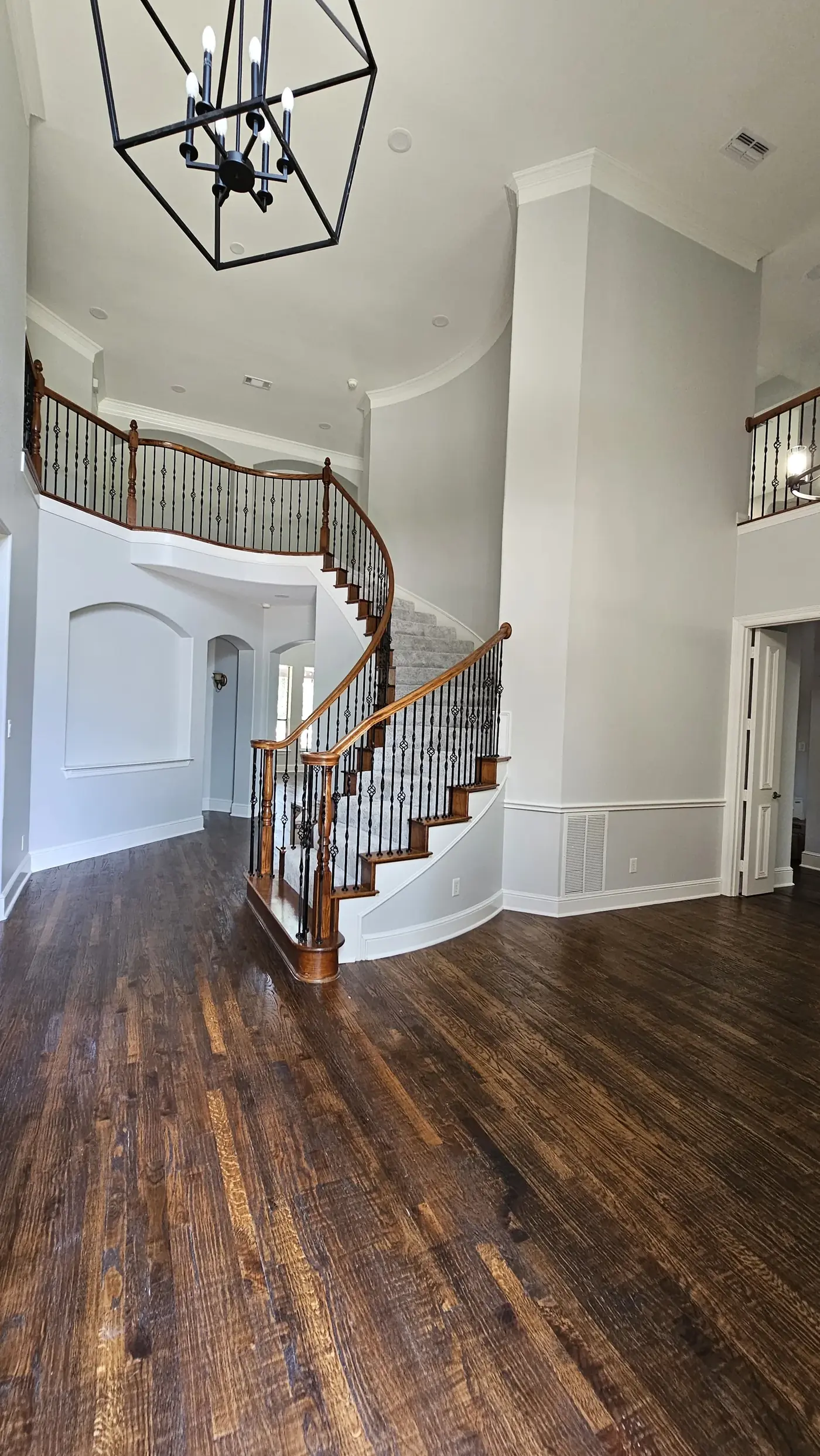 Curved staircase entry with modern chandelier